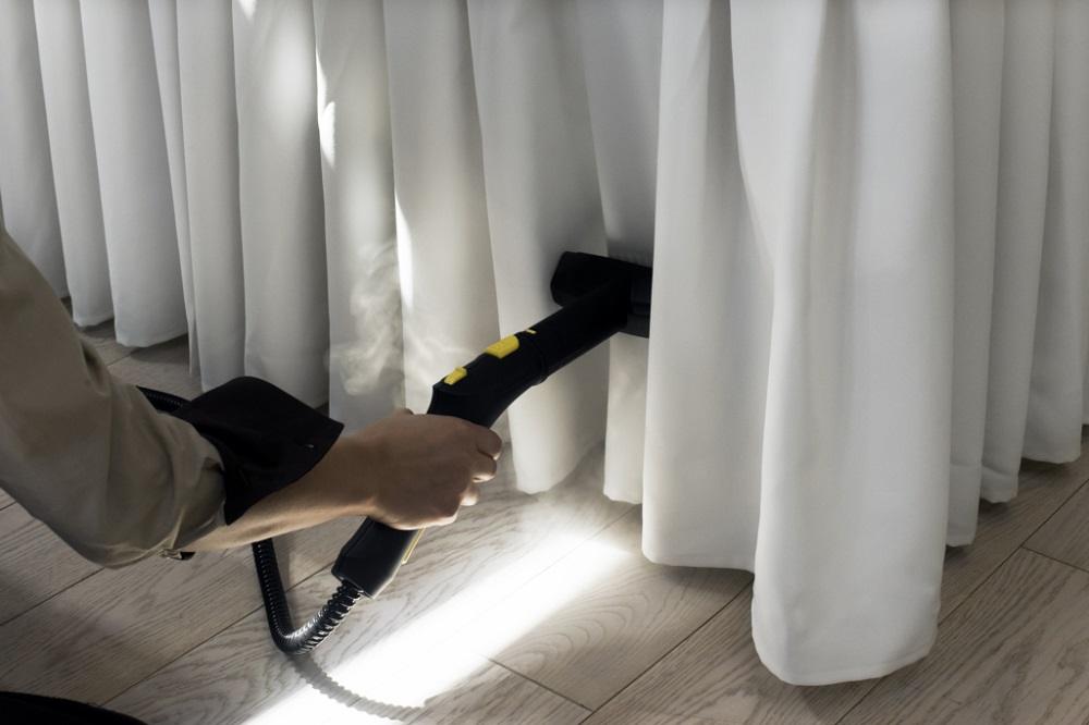 A cleaner steam-cleaning hanging curtains
